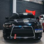 Front view of a sleek black Mitsubishi Lancer parked indoors in a garage setting.
